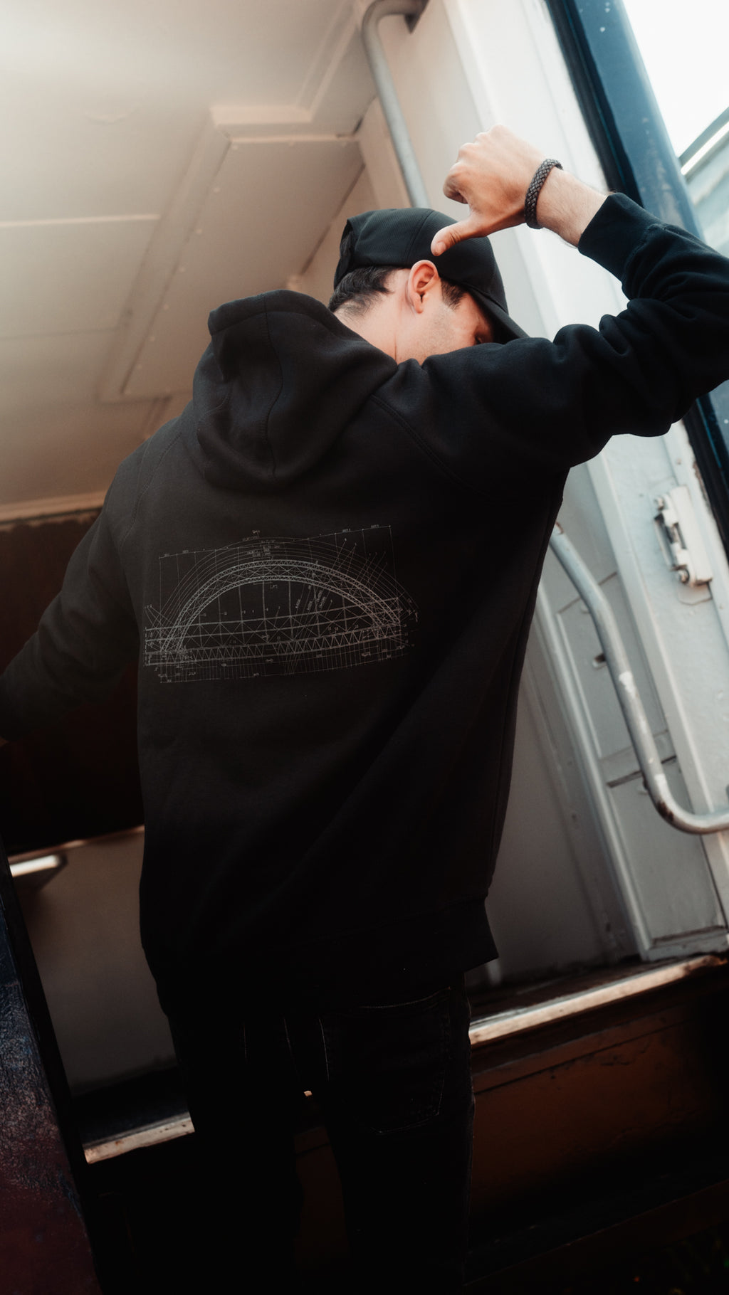 Ein Mann trägt einen schwarzen Kapuzen-Pullover mit einer schematischen Darstellung der Starlight Express Brücke aus der Show auf dem Rücken.